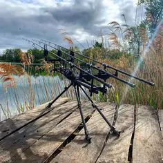 A beginner angler holding a fishing rod with a spinning reel attached, standing by the edge of a tranquil lake, illustrating the importance of quality fishing gear for beginners.