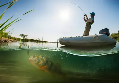 An angler casting a line into a serene lake at sunrise, capturing the peaceful beauty and anticipation of a day on the water through fishing photography.