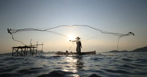 A person browsing a fishing website on a laptop, surrounded by fishing gear and equipment, illustrating the wealth of information and resources available online for anglers